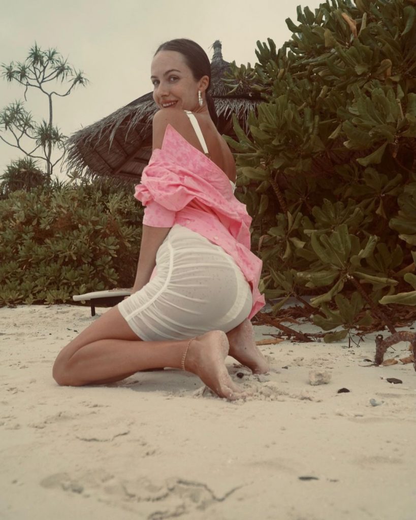 жена Остапчука на пляже соблазнительно присела в полупрозрачном платье 